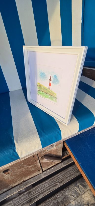 Leuchtturm List Aquarell Ein Strandkorb mit einem bemalten Bild von einem Leuchtturm und Himmel.