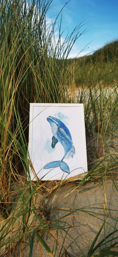 Wal Aquarell Ein blaues Fischgemälde vor hohen Grasbüscheln am Strand.